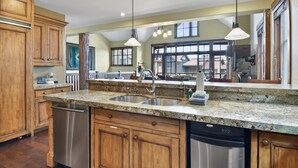 A spacious kitchen with granite countertops, stainless steel appliances, and wooden cabinetry.