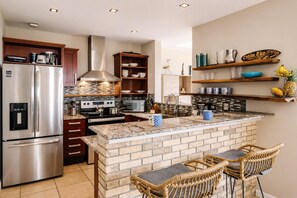 A kitchen with a stainless steel refrigerator, double ovens, a microwave, and a brick island with bar stools. - Amazing Ocean View Condo Close to the Beach w/Free Pickleball <br><br>Exclusive Pickleball Benefit:<br><br>As our guest, you'll receive complimentary pickleball access at 15 Love in Tamarindo. (Up to<br>two hours per day.) (Playa Langosta)