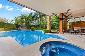 A swimming pool with a patio area, outdoor seating, and a view of the surrounding greenery. - Amazing Ocean View Condo Close to the Beach w/Free Pickleball <br><br>Exclusive Pickleball Benefit:<br><br>As our guest, you'll receive complimentary pickleball access at 15 Love in Tamarindo. (Up to<br>two hours per day.) (Playa Langosta)