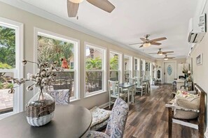 A spacious room with large windows, ceiling fans, and a dining area with chairs and a table. - *The Poolside Studio*-Lounge, Pool, Wifi (Jacksonville)