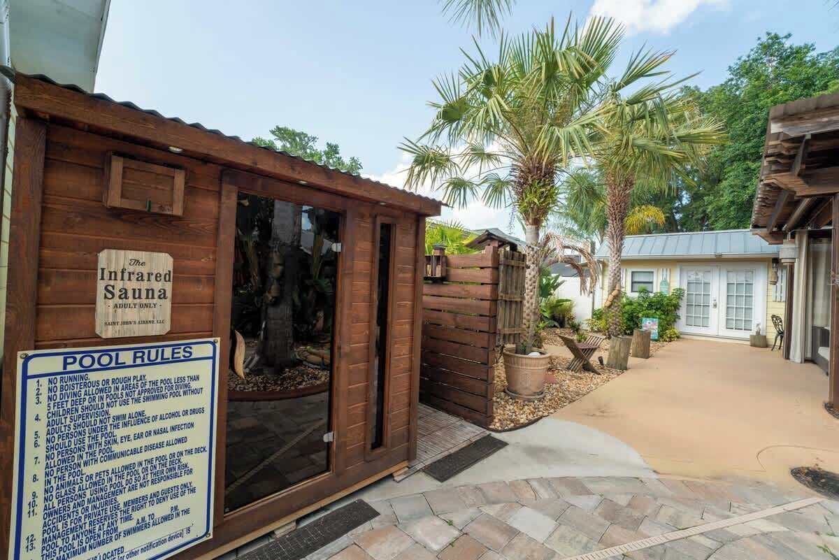 Un bâtiment en bois portant l’inscription « Le sauna infrarouge », avec un panneau affichant les règles à respecter à la piscine.