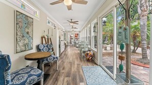A hallway with ceiling fans, a dining area with tables and chairs, and a view of the outdoors.