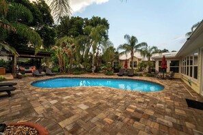 A swimming pool with a stone patio, surrounded by palm trees and lounge chairs. - *The Poolside Studio*-Lounge, Pool, Wifi (Jacksonville)