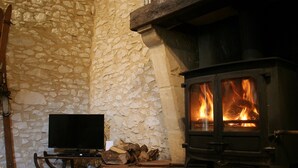 Ein Zimmer mit Stehwänden, einem Kamin, einem Fernseher auf einem Holzboden und brennendem Holz.