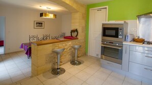 A kitchen with a stone arch, a microwave, oven, and a sink.