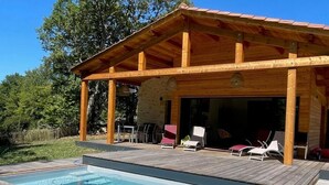 A wooden cabin with a pool and outdoor seating.