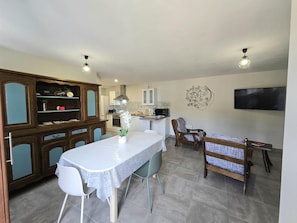 A compact living space with a dining area, kitchenette, and a flat-screen TV mounted on the wall.
