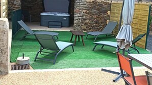 Een terras met een stenen muur, een barbecue en tuinmeubilair.