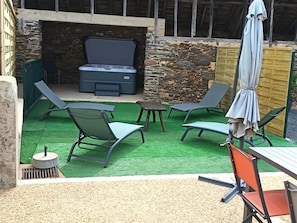 A patio area with a stone wall, a barbecue grill, and outdoor furniture.