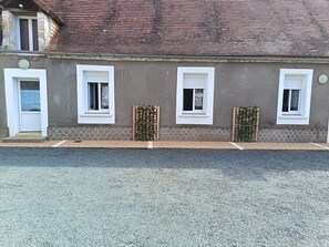 A building with a grey facade, three windows with white frames, and a door.