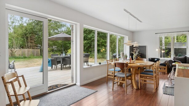 A spacious living area with a large sliding glass door leading to an outdoor patio, a dining table with chairs, a sofa, and a fireplace.