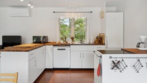 A modern kitchen with white cabinets, a wooden countertop, a built-in microwave, and a coffee maker.