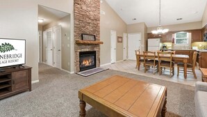 A living room with a fireplace, a dining area, and a kitchen.