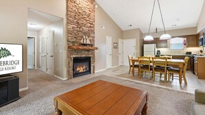 A living room with a fireplace, a dining area, and a kitchen. - King Bed Condo at StoneBridge Village Resort (Reeds Spring)