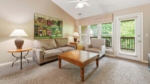 A living room with a sofa, coffee table, lamp, painting, and a ceiling fan. - King Bed Condo at StoneBridge Village Resort (Reeds Spring)