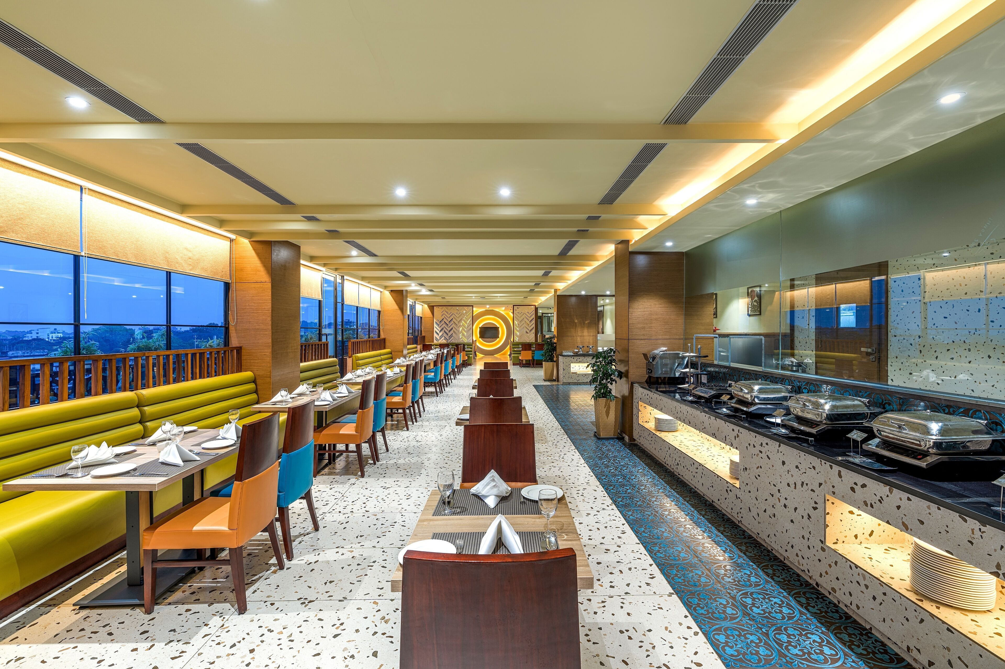 A restaurant with a long counter, booths, and a view of the cityscape.