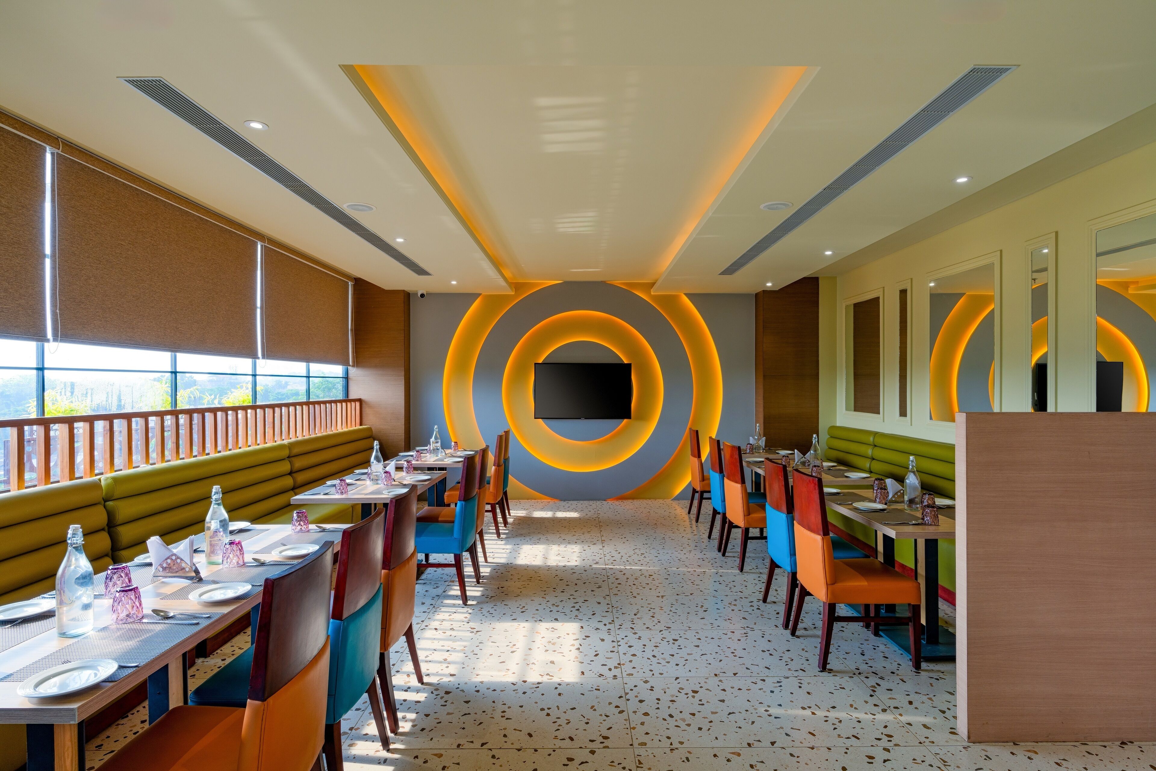 En modern restaurang med en lång bardisk, avskilda sittplatser och en stor TV-skärm.