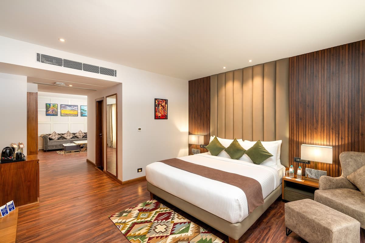 Une chambre d’hôtel moderne dotée d’un grand lit, d’un bureau, d’un canapé et d’un mur décoratif en bois.