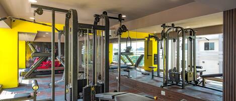 A gym with various exercise machines, a bench, and a mirror.