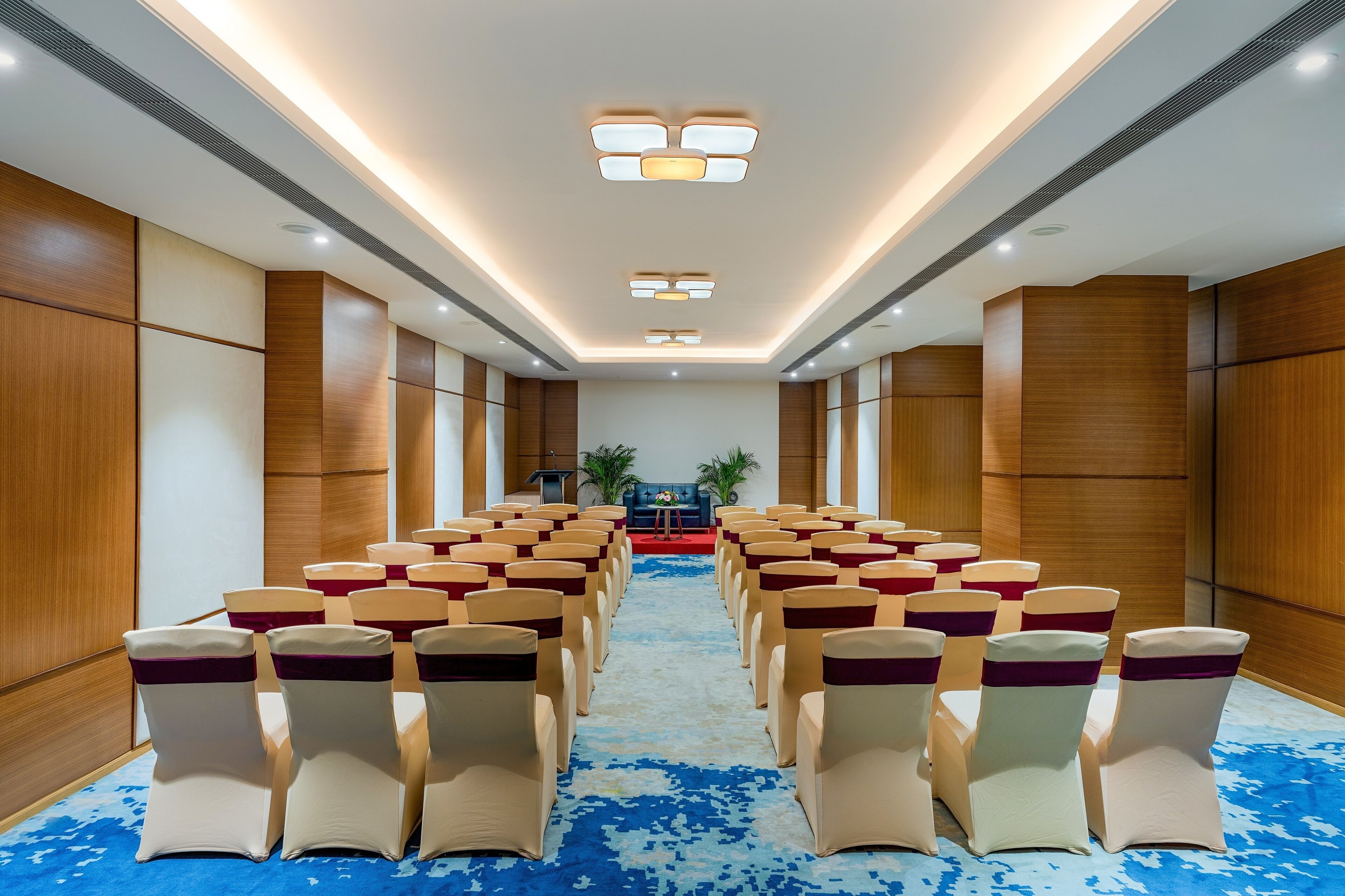 Un salón de conferencias con filas de sillas, un atril y un escenario.