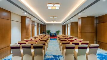 Un salón de conferencias con filas de sillas, un atril y un escenario.