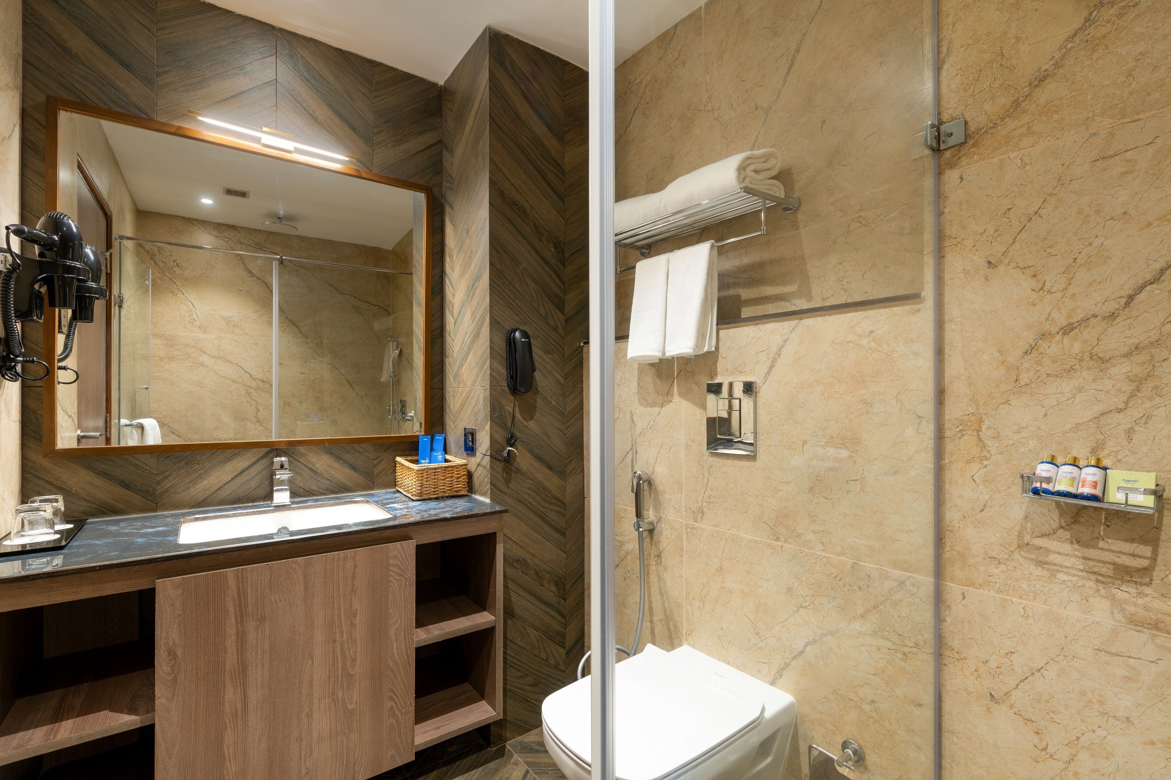A modern bathroom with a wooden vanity, a large mirror, a shower, and a toilet.