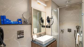 A modern bathroom with a large mirror, a sink, and a shower area.