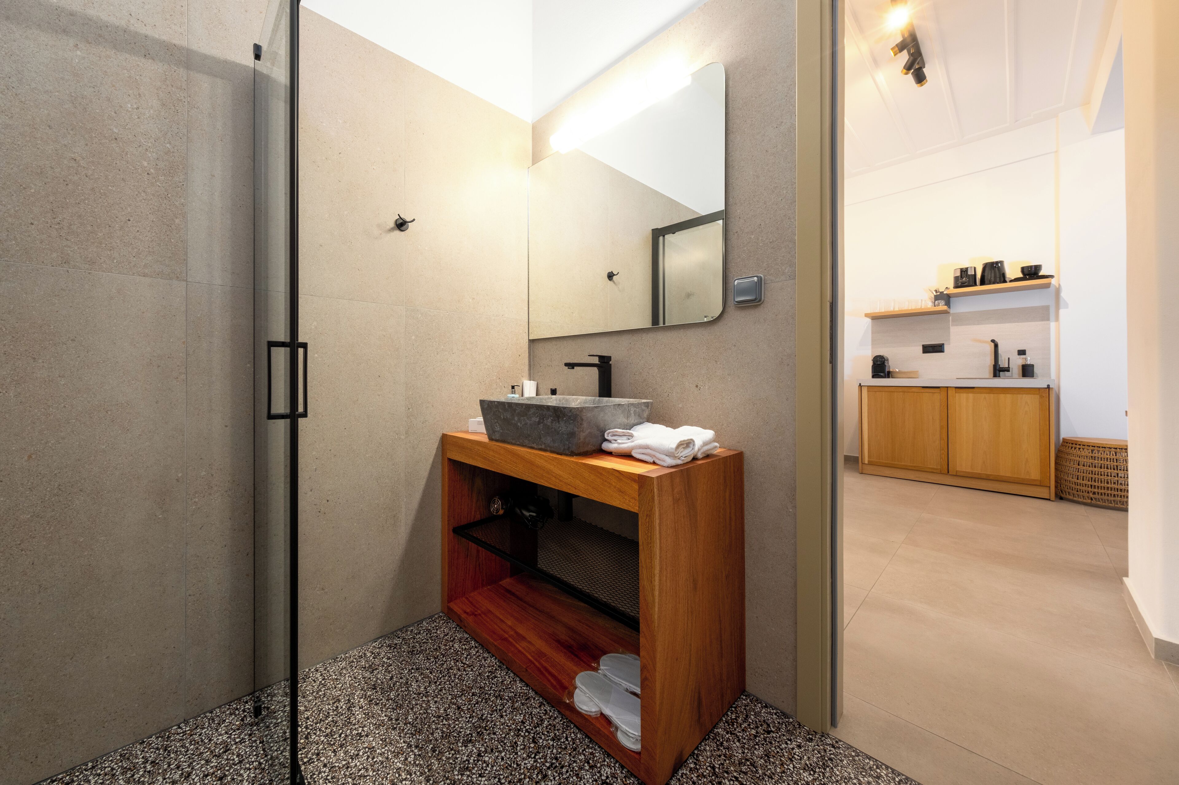 A modern bathroom with a glass shower enclosure, a wooden vanity with a basin, and a mirror.