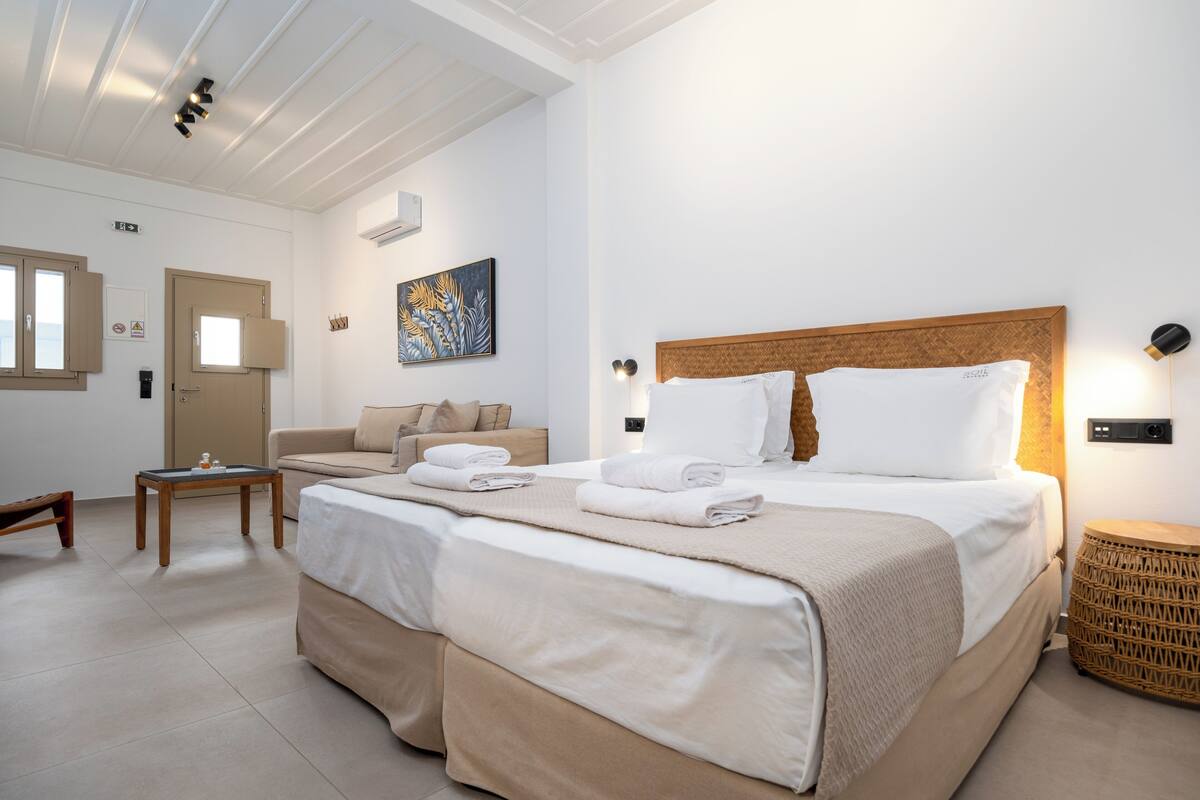 Une chambre d’hôtel avec un grand lit, un canapé, une petite table et une lampe fixée au mur.