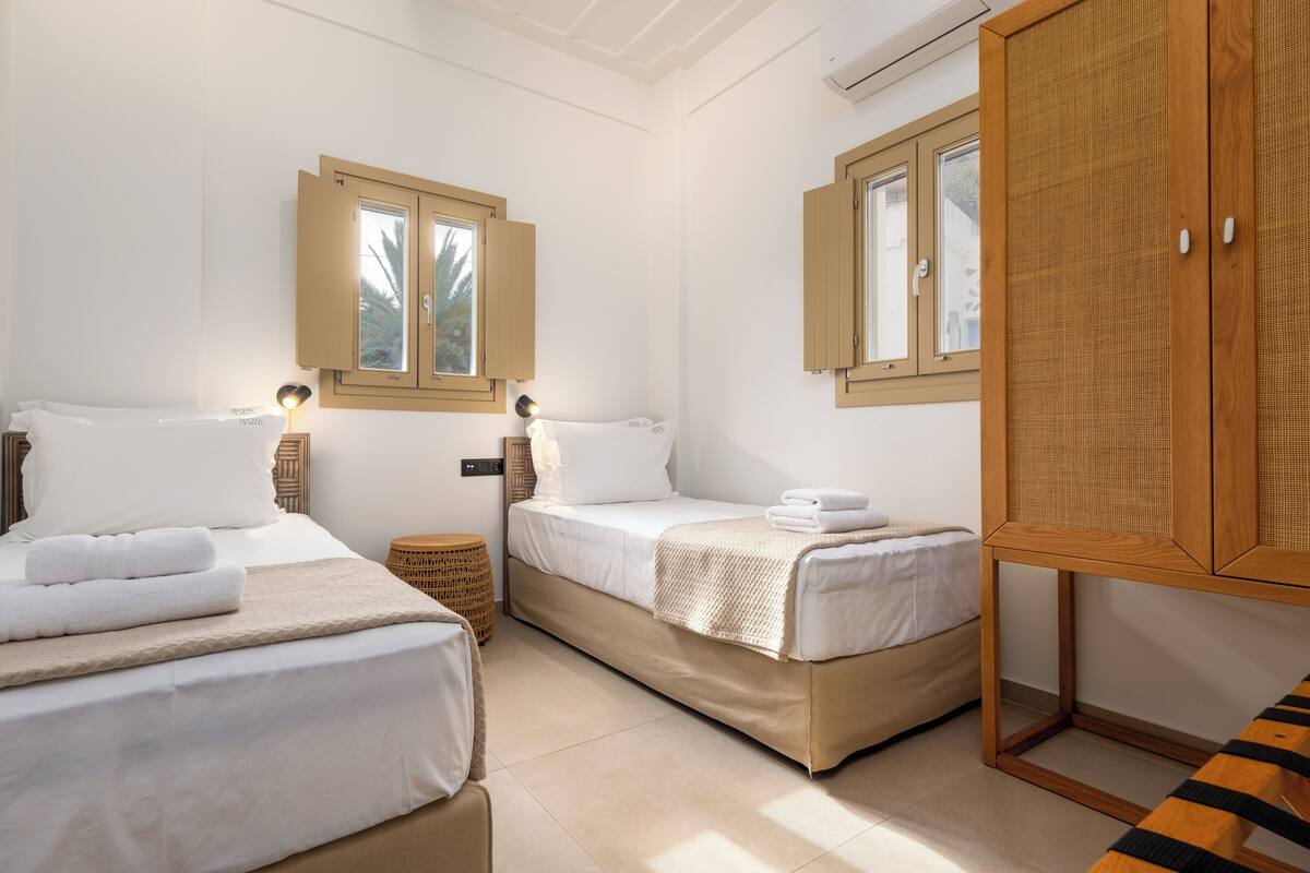 Une chambre d’hôtel avec deux lits, une armoire en bois et une fenêtre avec des volets.