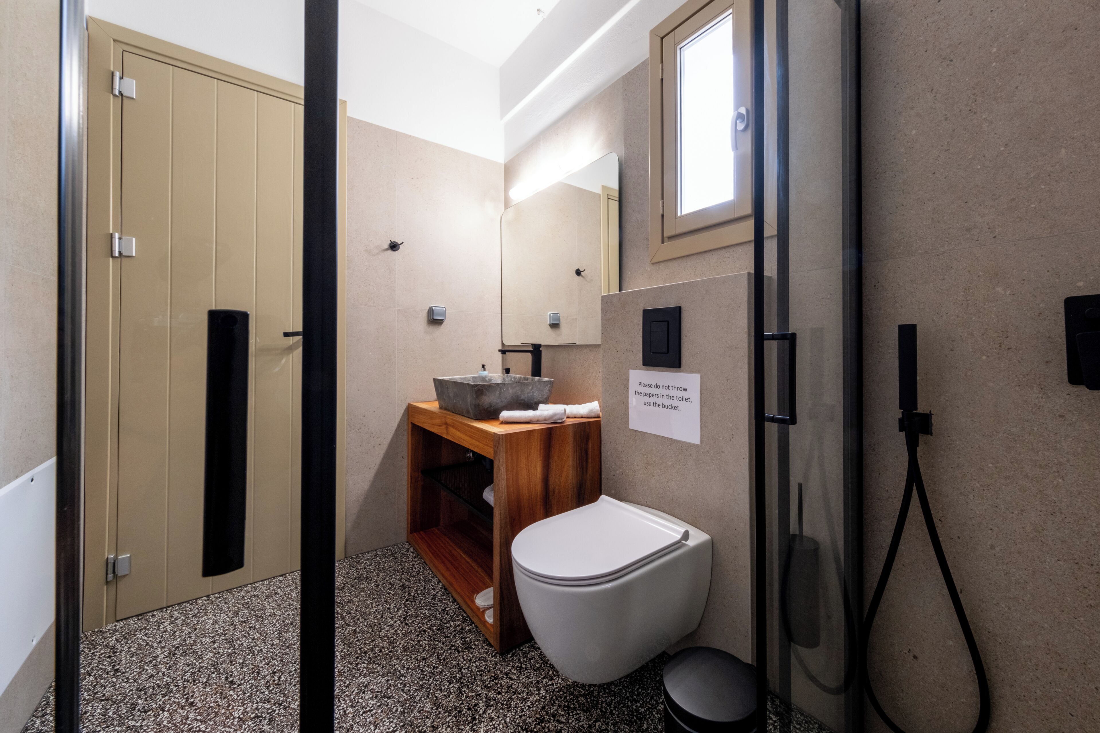 A bathroom with a toilet, sink, mirror, and shower.