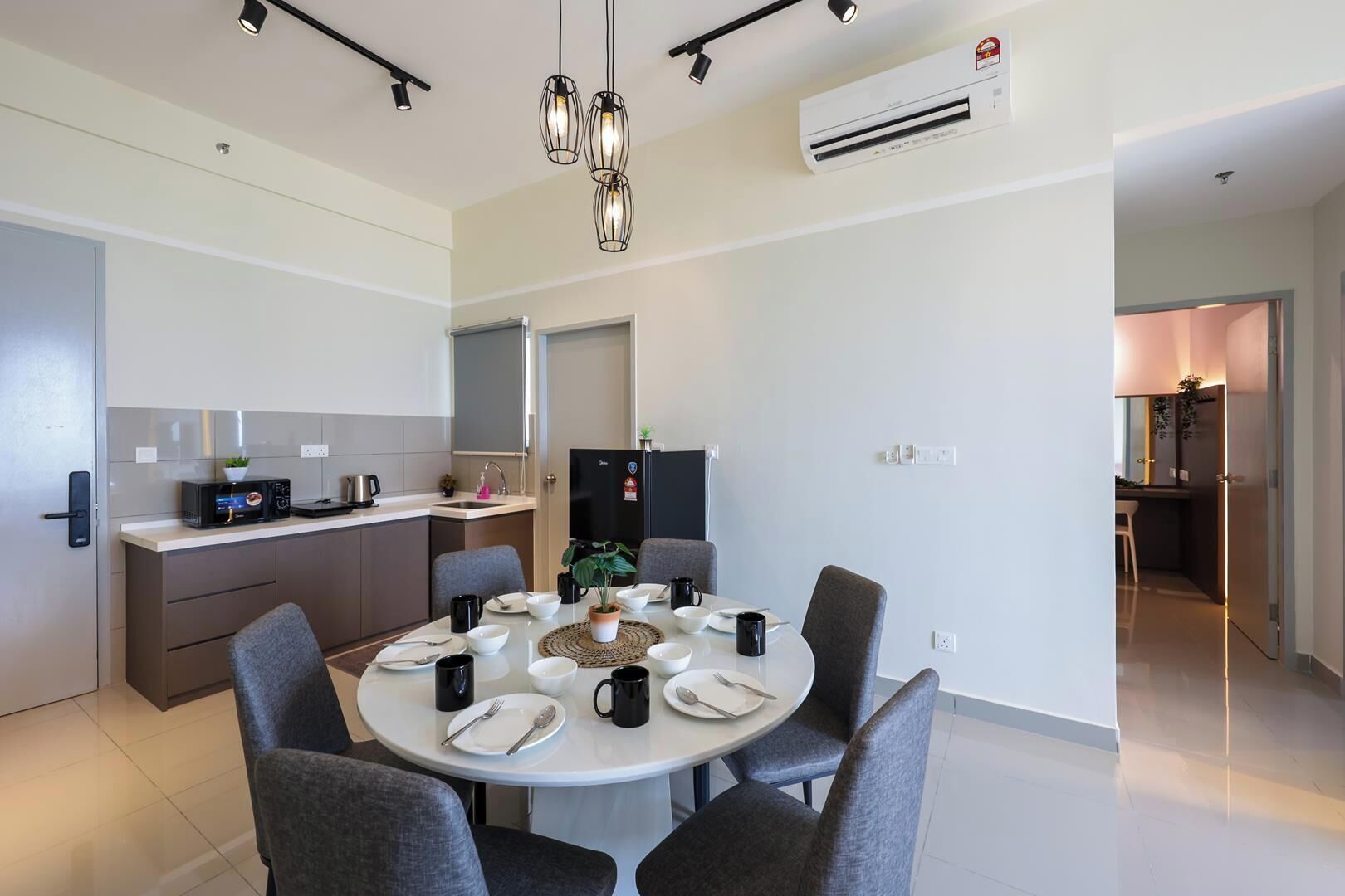 Una cocina moderna con comedor, que incluye una mesa redonda con sillas, horno empotrado y refrigerador.