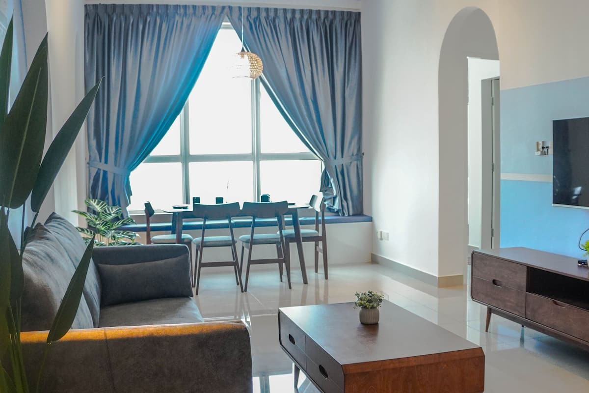 A modern living room with a sofa, coffee table, TV, and dining area.