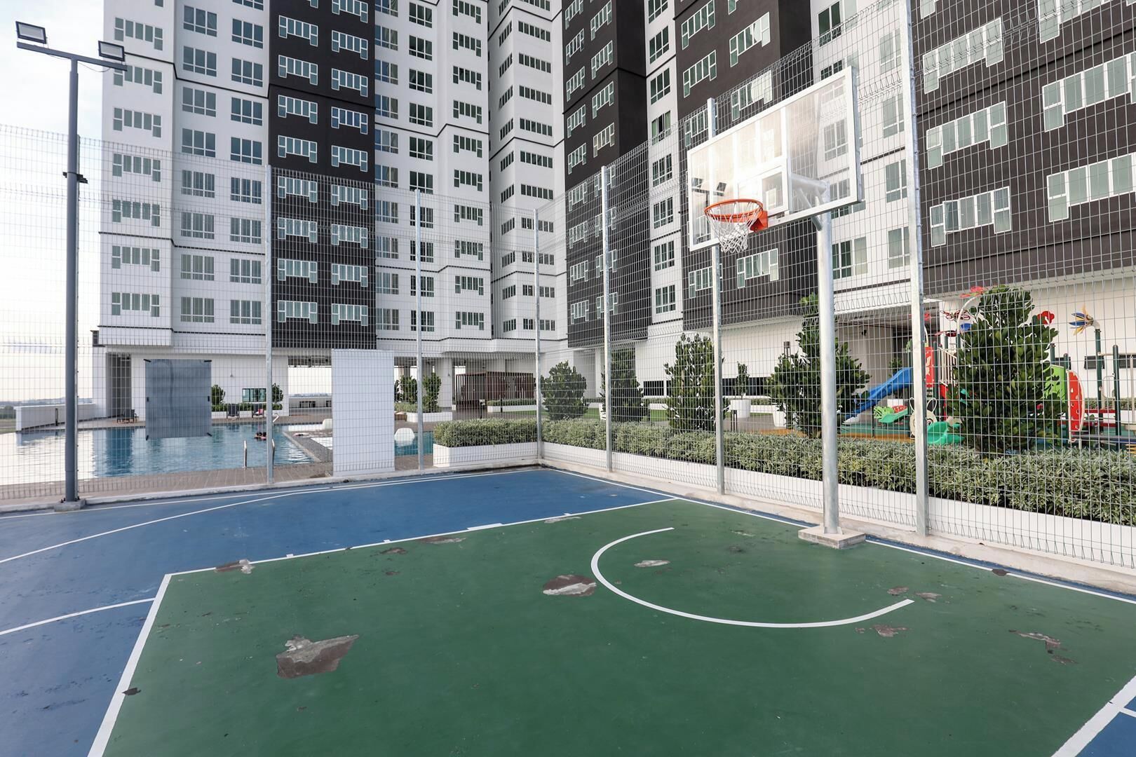 Eine Basketballhalle mit Netz, umzäunt und neben einem Schwimmbecken.