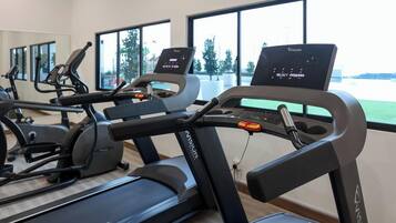 A gym with treadmills, stationary bikes, and a rowing machine.