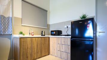 A modern kitchen with wooden cabinets, a black refrigerator, a microwave, and a sink.