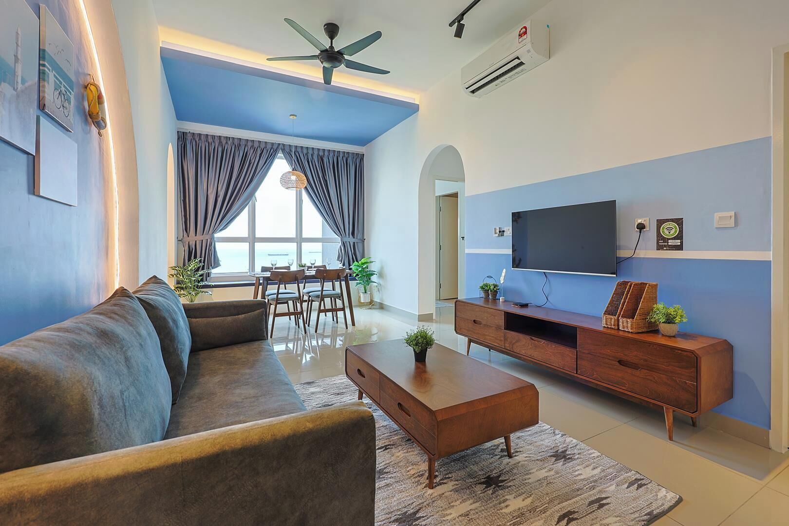 A modern living room with a sofa, coffee table, TV, and dining area.