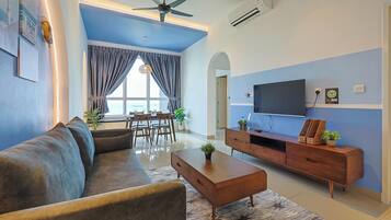 A modern living room with a sofa, coffee table, TV, and dining area.