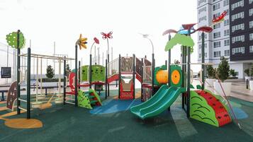 A playground with slides, climbing structures, and a fenced play area.