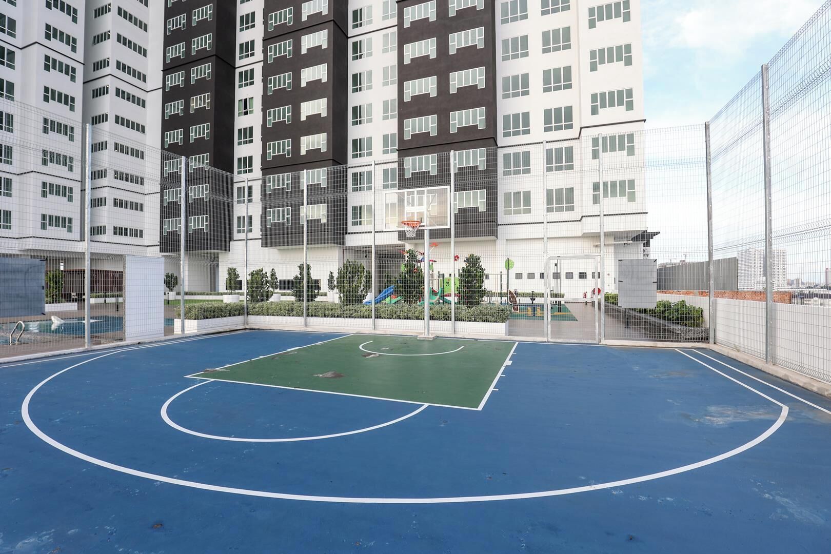 Een buitenbasketbalveld omringd door hoge wooneenheden.