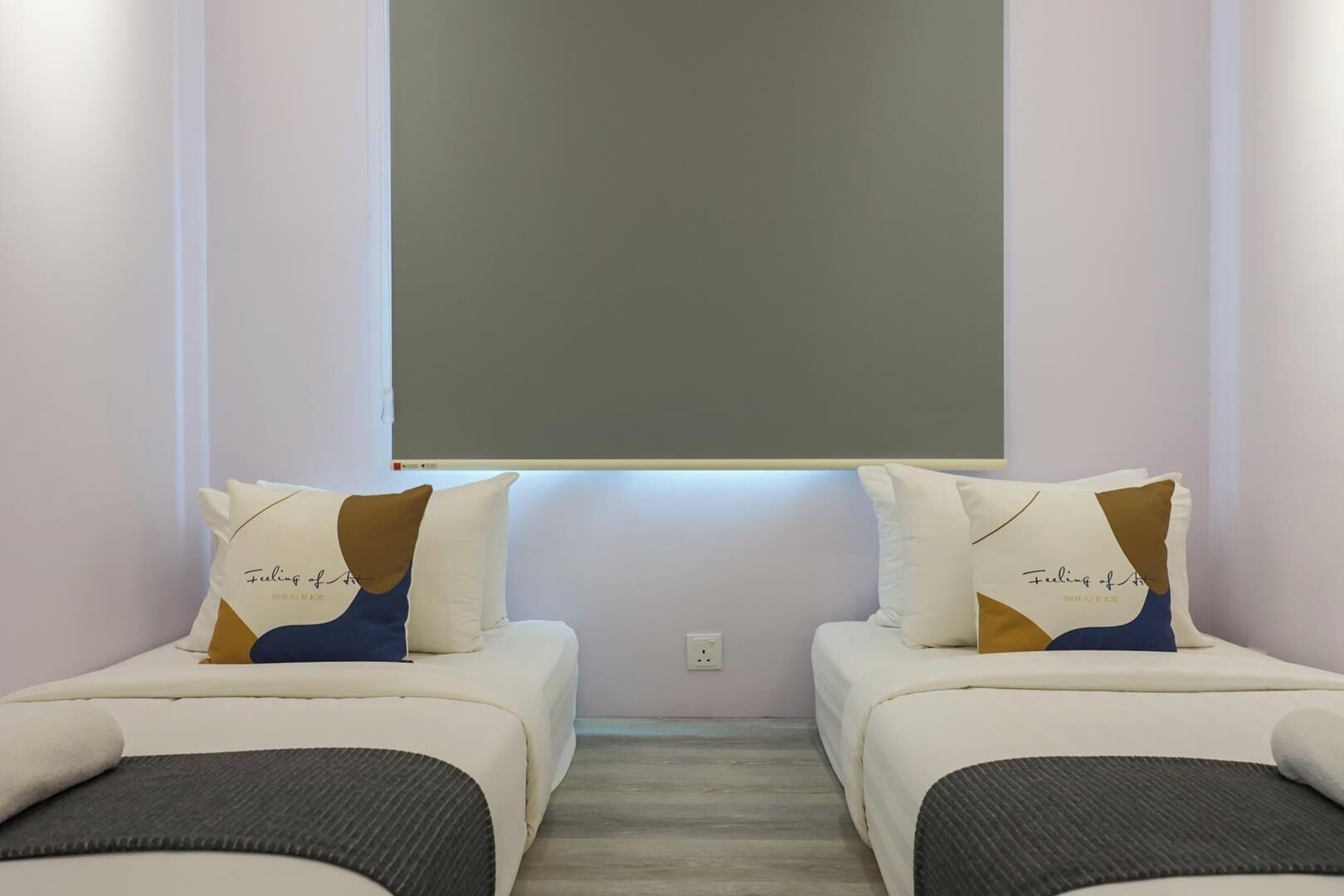 Une chambre avec deux lits, chacun étant équipé d’un oreiller orné d’un motif et d’un texte.