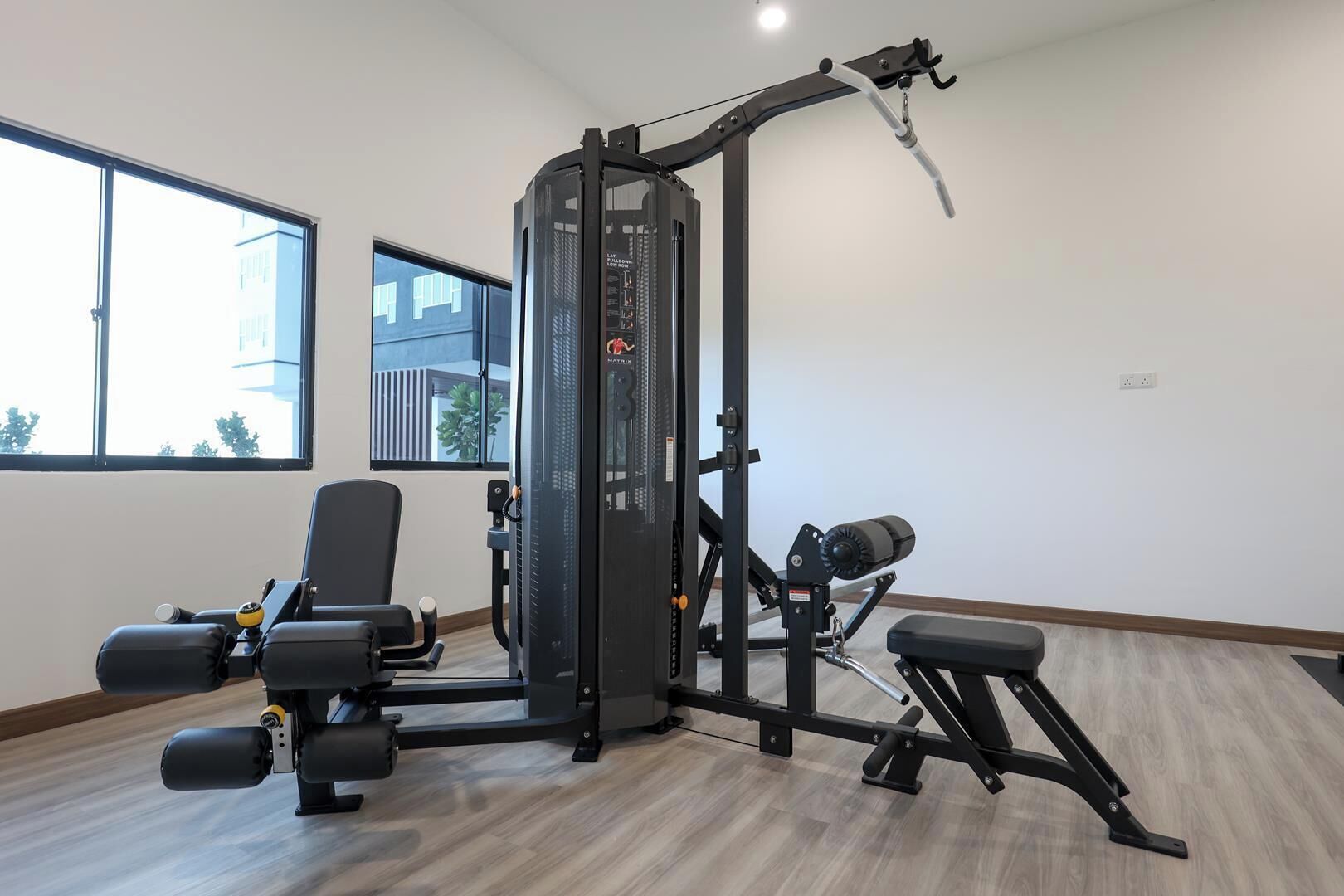 A gym with a weight machine, a bench, and a window with a view of buildings.