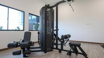 A gym with a weight machine, a bench, and a window with a view of buildings.