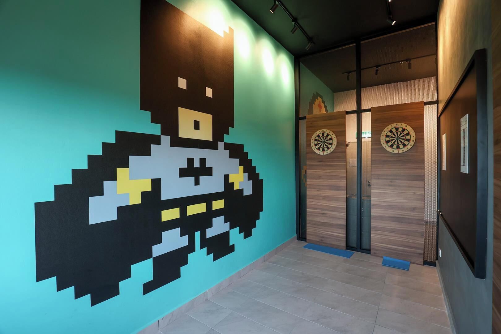 A hallway with a pixelated wall art, a dartboard, and a wooden door.