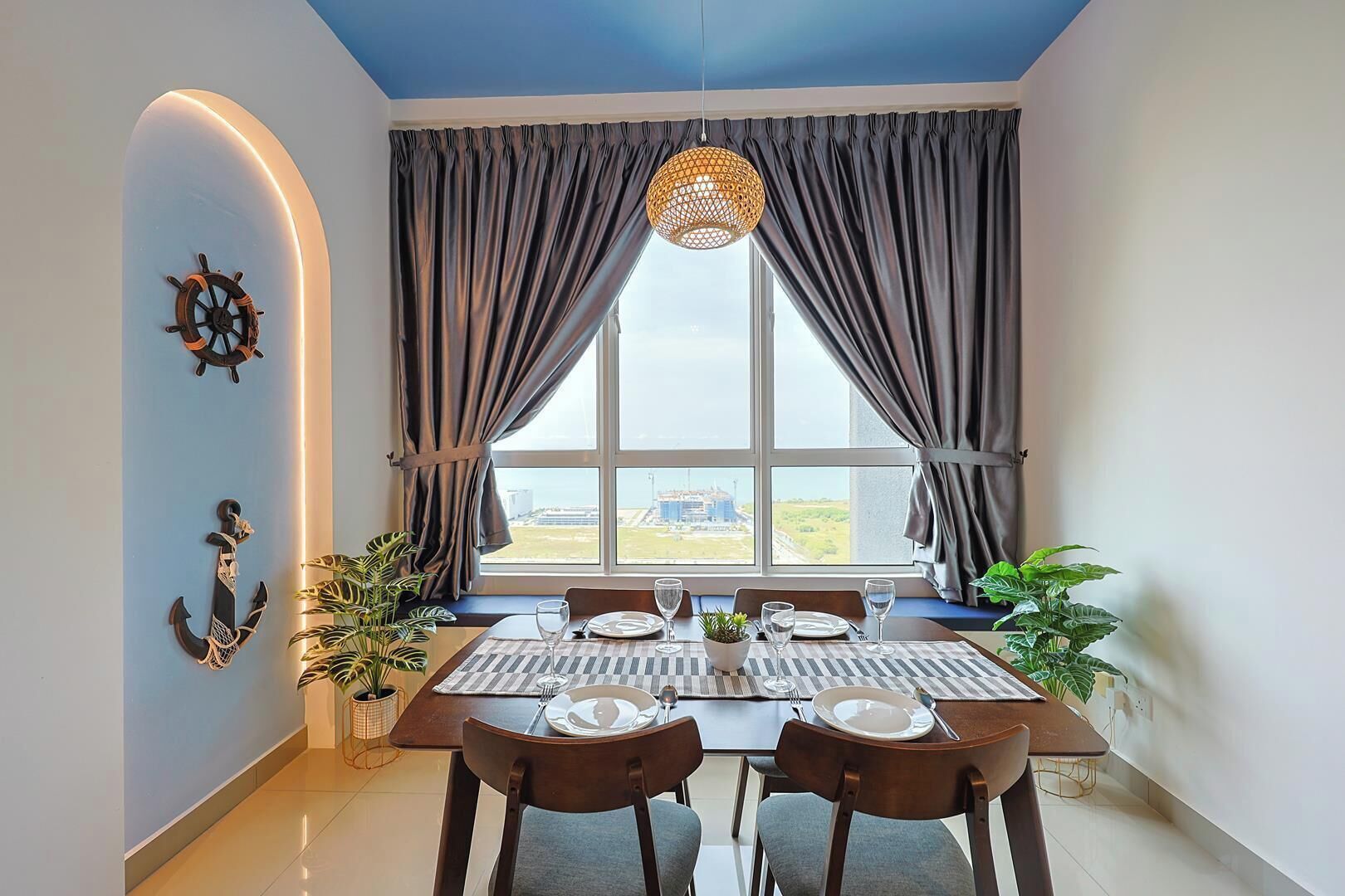 A dining area with a table set for four, a view of the outdoors, and a ceiling with a unique design.
