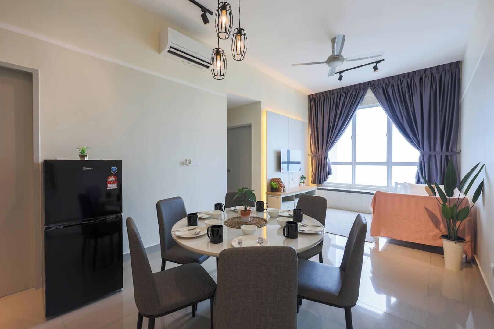 A modern dining area with a round table, chairs, and a black refrigerator.