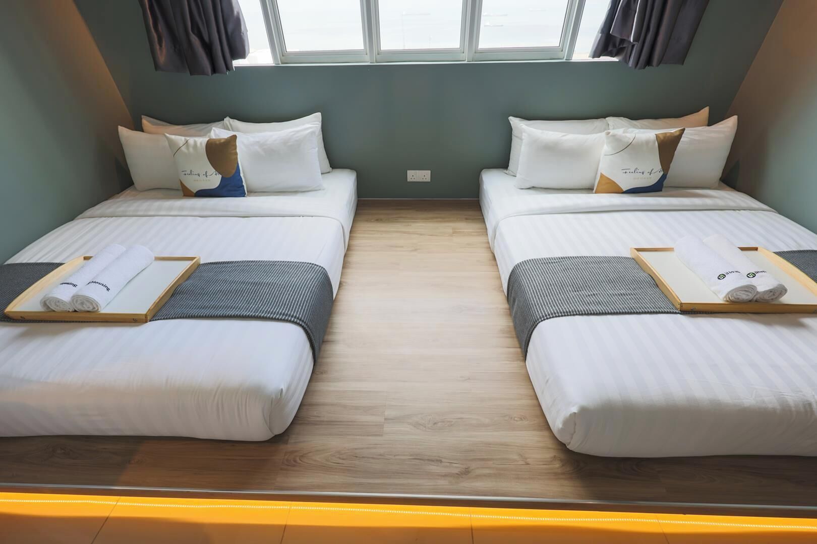 A twin room with two beds, each with a pillow and a tray with towels.