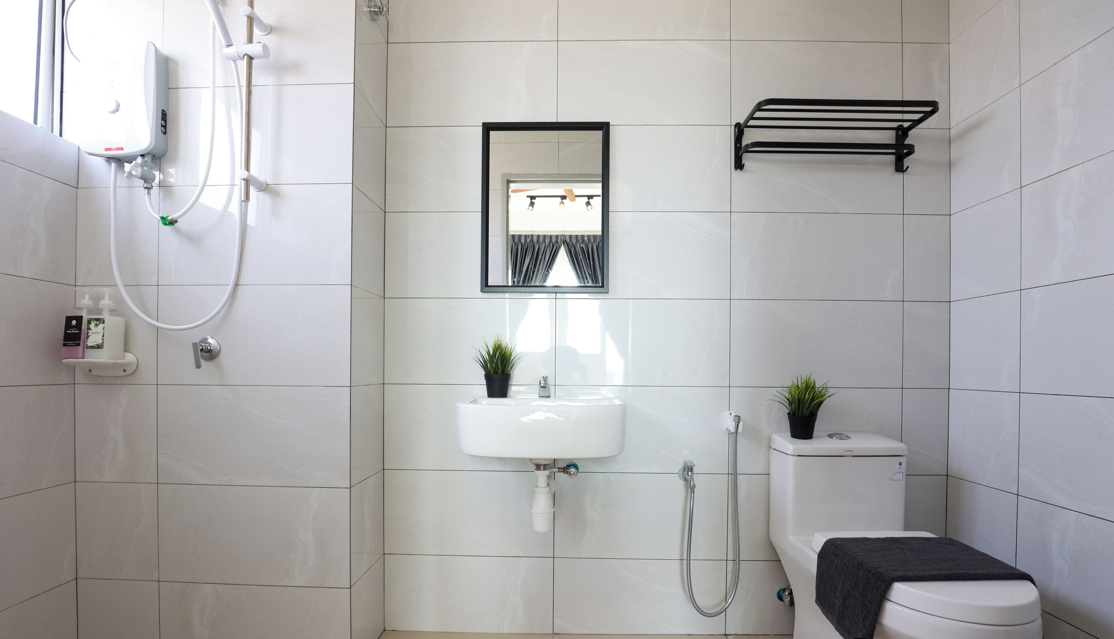Een moderne badkamer met een wit wastafel, een spiegel, een toilet en een douche.