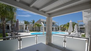 A covered outdoor area with a pool, lounge chairs, and umbrellas. - PietraBianca Marzamemi (Syracuse)