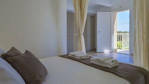A hotel room with a bed, pillows, a neatly folded towel, and a balcony with a view. - PietraBianca Marzamemi (Syracuse)